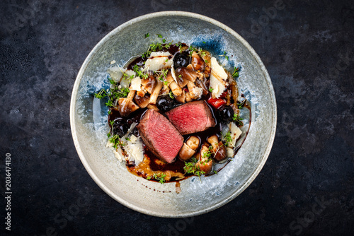 Foto Roasted venison steak from haunch with wild mushrooms volvaria volvacea, black c