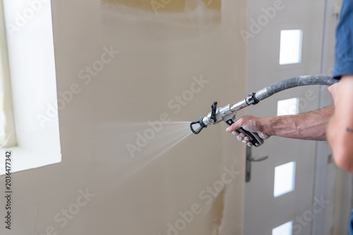 Application mécanique d’un revêtement mural par projection airless lors de travaux de finition intérieure sur un chantier de rénovation.