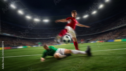 Fotografie Soccer player jumping over sliding opponent with motion blur in stadium match