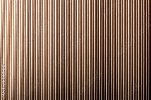 Vertical wooden slats in warm light. Abstract interior wall texture with repeated lines. Architectural background for design and decor..