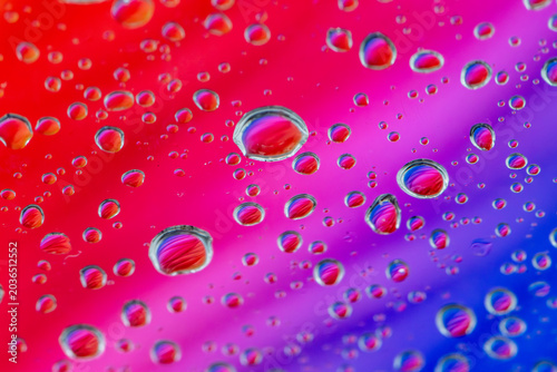 An array of water droplets scattered across a vibrant, gradient background of red, pink, and purple