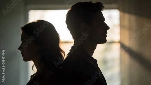 Silhouette of a man and woman in a breakup scene, standing apart with emotional distress. Cinematic lighting highlights the sorrow and tension between a couple facing a difficult moment.