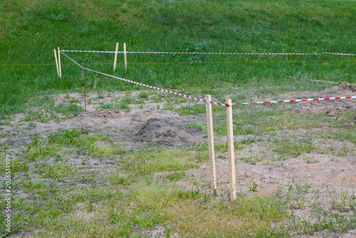 Fotografie A construction site shows wooden stakes and red and white tape marking the boundaries of the area