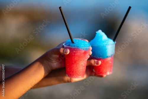 Bild auf Leinwand Pair of hands holding two red blue slushies