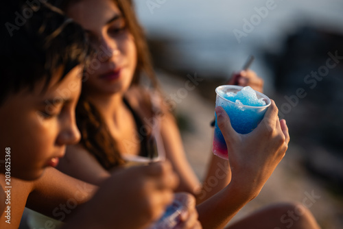 Photography Children enjoying refreshing blue slushy drinks during summer sunset