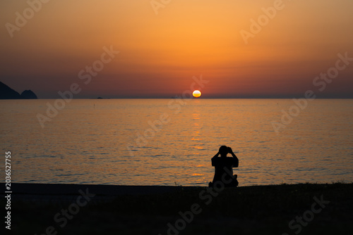 夕日の海を眺める人物シルエット