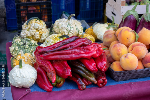 Red peppers, pumpkins and peaches.Vibrant Farmers’ Market Stall with Fresh Organic Produce. Colorful Vegetables and Fruits in Natural Light