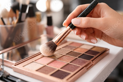 Close-up of cosmetic brush on eyeshadow palette, symbolizing beauty care, makeup artistry, and elegance