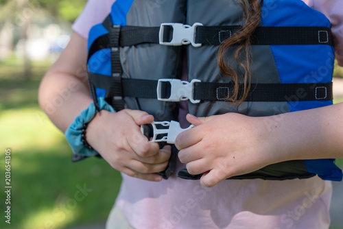 Close up of hands buckling a life jacket vest for water safety outdoors