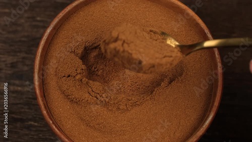 Scoop with spoon Cinnamon powder, close up. Warm, aromatic spice is a staple in baking and cooking