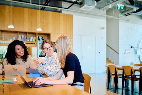 Fotografie Three diverse women working together on laptops and a tablet, discussing ideas i