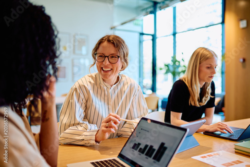 фотографія Diverse businesswomen collaborating and having a discussion in a bright office,
