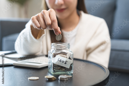 Fotografía Saving money wealth concept, asian young business woman hand putting coin into jar for saving cost, cash finance planning to spend enough money on her income for save money, payment tax, investing