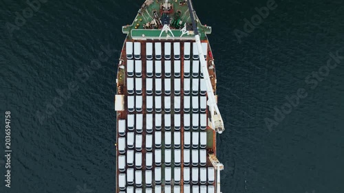 Top aerial view, A transport ship arrives at the port of Halifax, Canada. The ship carries many vehicles for export. Workers prepare to unload cars and handle cargo operations