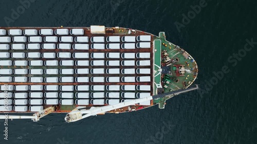 aerial view, A cargo ship is in the port of Halifax, Canada. The ship carries many cars for export. The view shows the layout of cars and shipping containers on the deck