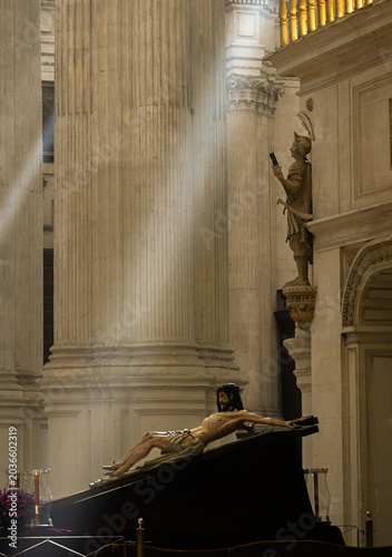old sculpture of Jesus Christ on the cross illuminated by soft beams of sunlight, in Granada Spain