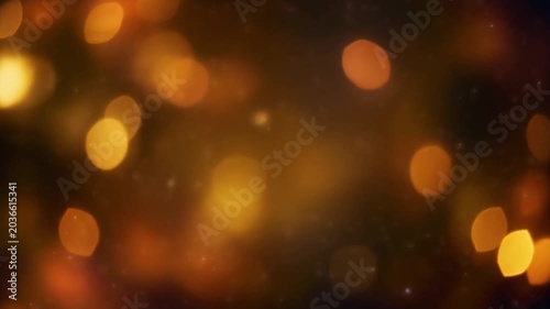 Abstract background of warm golden bokeh lights floating and fading in dark space.

