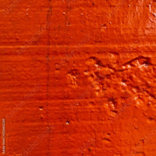 Red textured painted wall surface with rough grunge pattern closeup