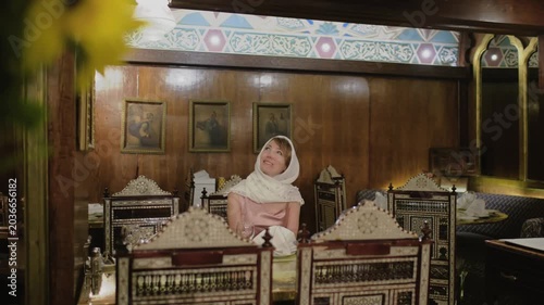 4K travel video in Cairo, Egypt, with cinematic focus transition from bright sunflowers to a smiling woman sitting in a traditional oriental restaurant interior.