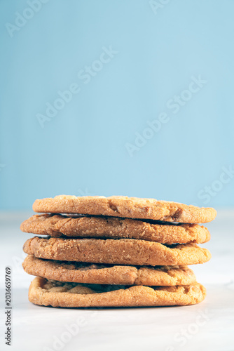 Vertical shot of five homemade golden cookies stacked neatly on top of each other with beautiful minimalistic backdrop