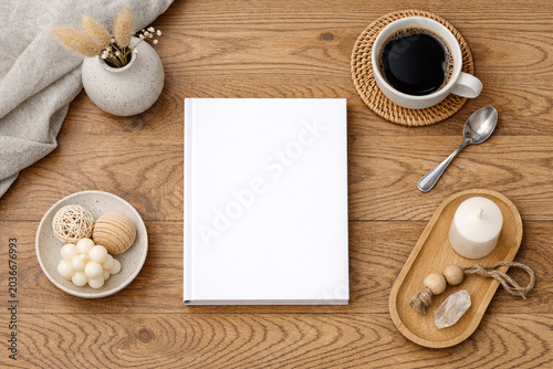Organized coffee table with a blank notebook, wooden spoon, bowl of seashells, and cup of coffee.