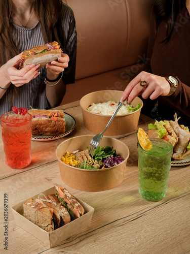 Girl eating sandwich. Girl eating salad. Healthy food table