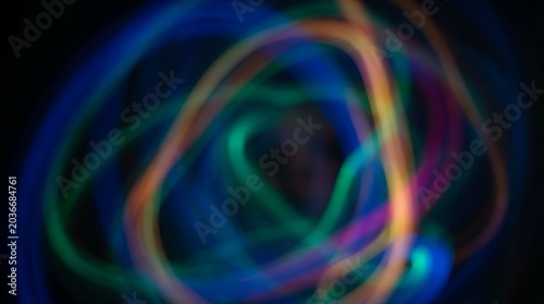 Abstract colorful glowing neon light trails on dark background.