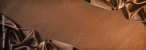 Black dark chocolate coffee copper brown silk satin. Shiny silky smooth fabric. Soft folds. Draped. Elegant luxury background. Empty blank template design ad. Wide banner. Flat lay, table top view.