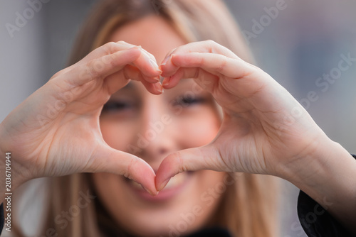 Foto hands shaped like a love and heart with a smiling young woman