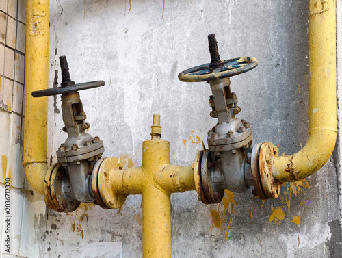 фотографія Gas pipeline valves mounted on the outside facade of a residential house with ye