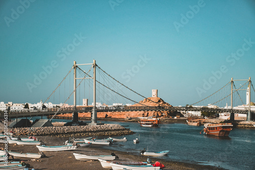Tableau sur toile Panoramic view of Al Ayjah bridge, historic watchtowers, and city skyline in Sur
