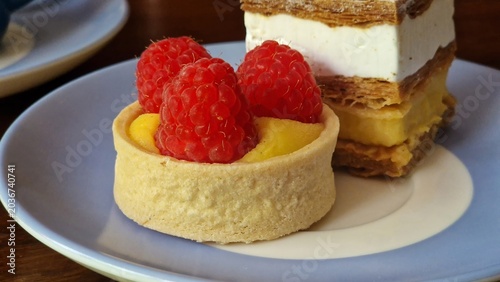 Sweet raspberry tart and creamy vanilla mille-feuille served on a light blue plate
