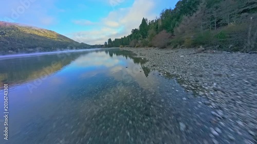 Low Aerial FPV Glide Over Clear Lake Shore and Pebbles