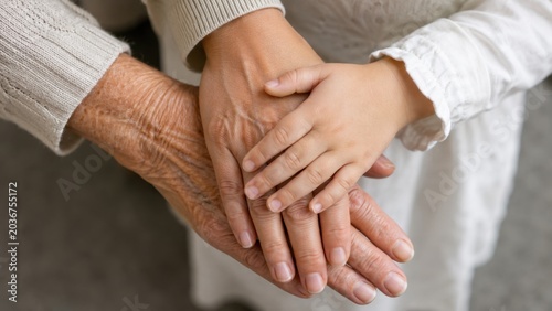 Child holding elderly hands in supportive familial setting