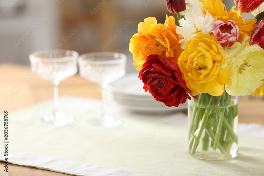 Obraz premium Beautiful tulips in vase on wooden table in kitchen, closeup. Space for text