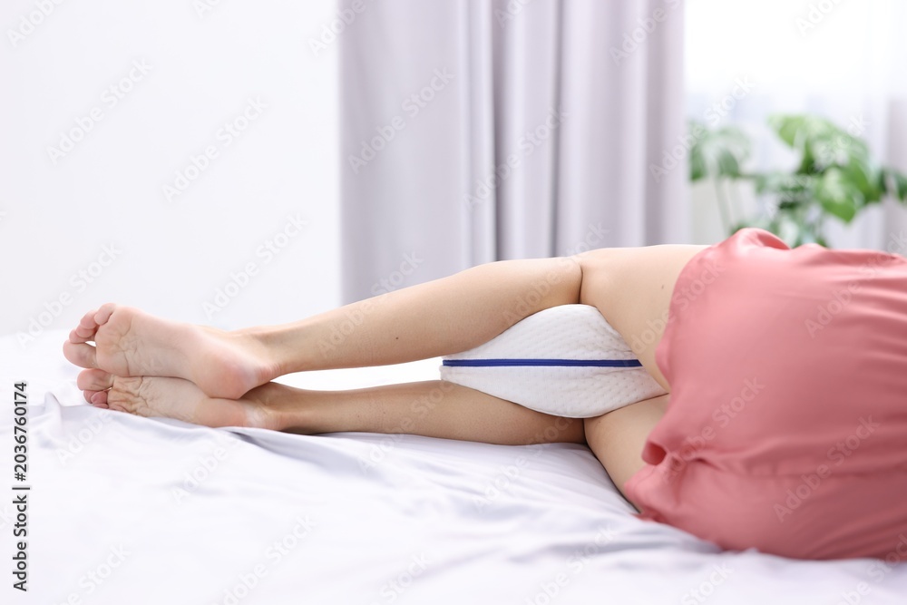 Obraz premium Woman sleeping with orthopedic pillow between her legs on bed at home, closeup. Space for text