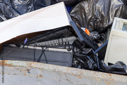 Pile of discarded computer keyboards and electronic components in a recycling bin. Electronic waste management and hardware disposal. Concept of technological obsolescence and pollution