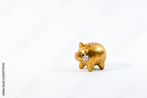 A shiny gold pig figurine holding a flower in its mouth isolated on a clean white background