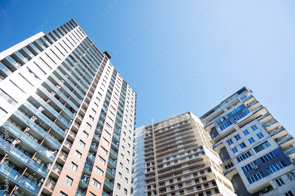 Fototapeta premium Urban high-rise buildings with a central unfinished tower in bright daylight