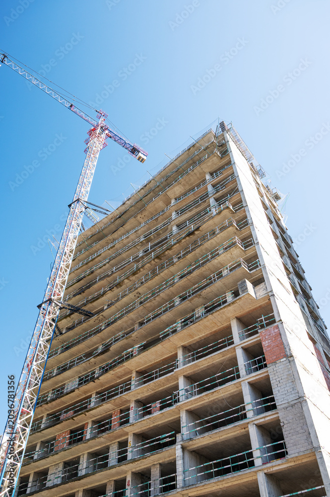 Fototapeta premium High-rise building under construction with tower crane, urban development and real estate concept