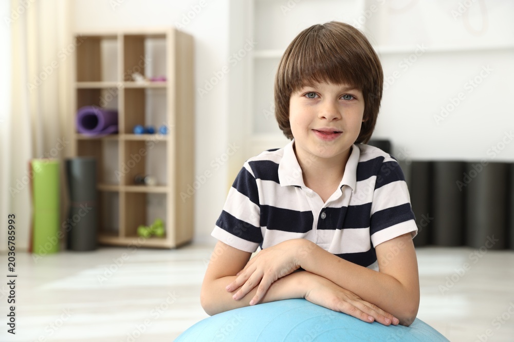 Fototapeta premium Cute little boy with fitness ball indoors, space for text
