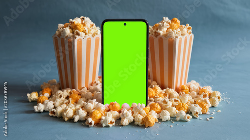 Smartphone Green Screen Mockup with Scattered Popcorn and Striped Buckets on Blue Background for Movie Night Cinema App and Video Streaming Presentation High Resolution