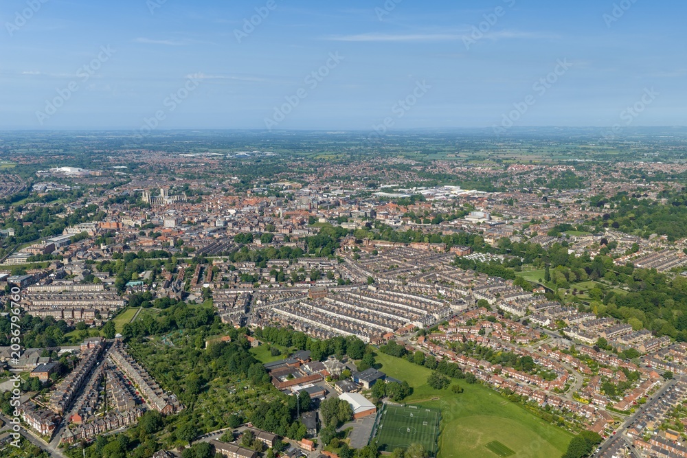 Obraz premium Panoramic aerial drone view of the historic city of York North Yorkshire England showing York Minster residential housing green parkland and countryside beneath a clear blue sky in the summer time