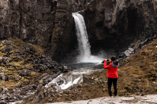 Fotografía Randonneuse prenant en photo une cascade encaissée entre des falaises basaltique