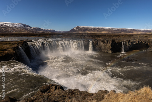 Slika na platnu Cascade puissante dans un paysage naturel sauvage avec embruns et ciel dégagé