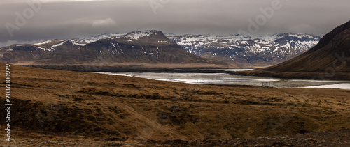 Schilderij op canvas Un vaste paysage islandais s'étend entre des montagnes aux sommets enneigés et un fjord aux eaux calmes