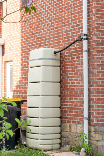Photos Modern slimline rainwater tank installed against a red brick wall of a residential house