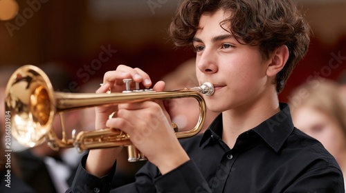 Teenage boy playing trumpet in a school orchestra performance
