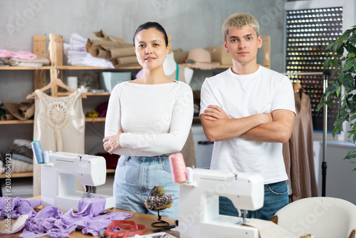 Photography Positive young male and female dressmakers standing in sewing studio ready to gr