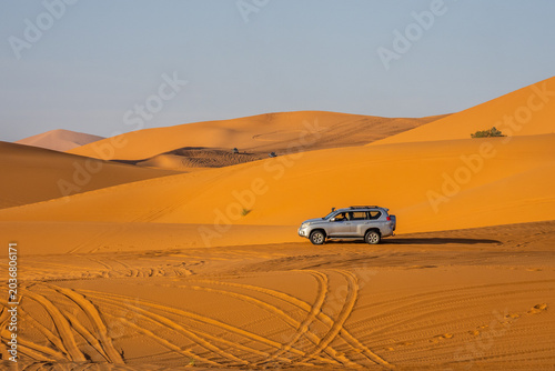 Off-road SUV crossing golden Sahara dunes near Merzouga, Morocco